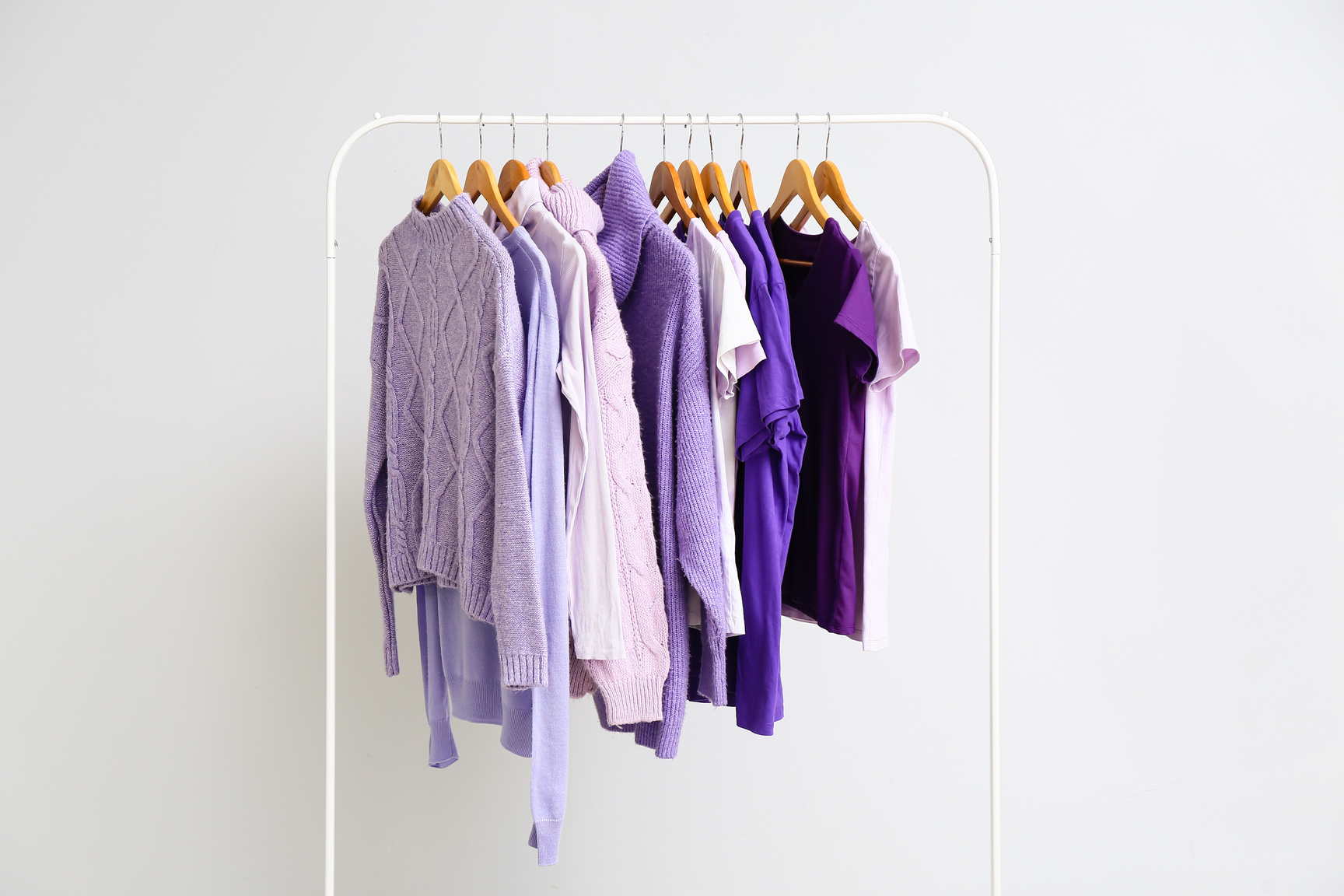 Rack with Clothes in Purple Shades on Light Background